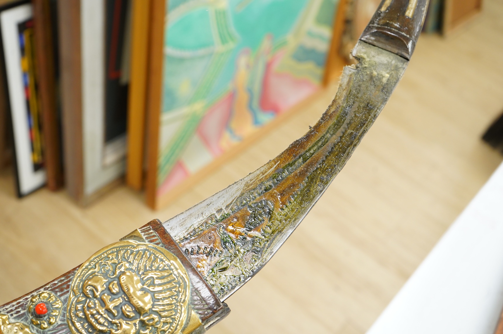 A decorative Indian axe, the large head inlaid with brass Hindu figures, together with a brass mounted North Indian kukri, another similar knife with bone handle, and a large shovel-shaped copper and brass item possibly